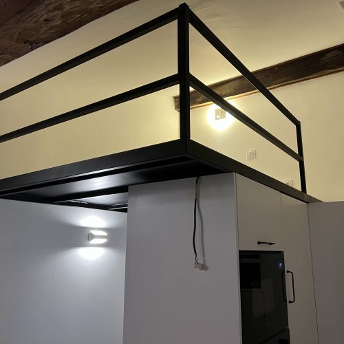 Mezzanine métallique sur mesure installée dans un studio rénové à Lyon, intégrée à l'agencement de la cuisine