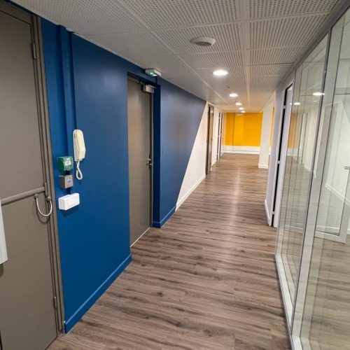 Couloir de bureaux rénové avec sol bois et cloisons vitrées – Cadencia Lyon 3