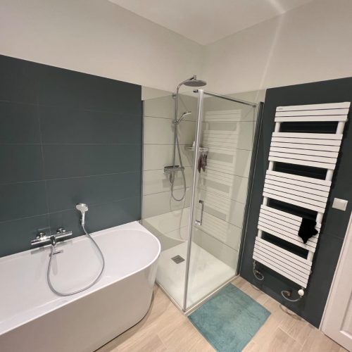 Salle de bain avec baignoire îlot, douche vitrée et sèche-serviettes design