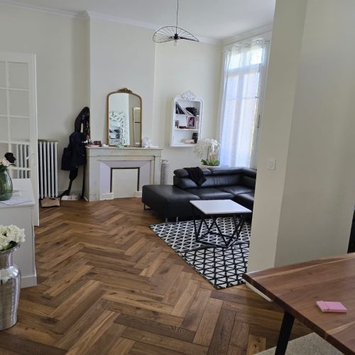 Rénovation d’un salon haussmannien à Lyon avec cheminée d’époque, parquet en chevron et mobilier contemporain