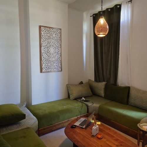 Salon rénové avec banquettes vertes, table basse en bois et suspension orientale à Lyon